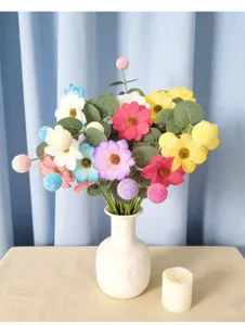 Detailansicht eines bunten künstlichen Gänseblümchen- und Eukalyptusstraußes in weißer Vase.