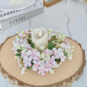 Gros plan détail d'une couronne de bougie de fleurs artificielles roses et blanches sur bois.
