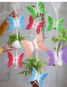 Farfalle colorate di carta con clip su appendini in macramè per arredo interni