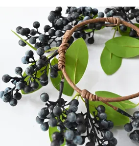 Close-up of artificial black berry wreath with green leaves for Christmas decor