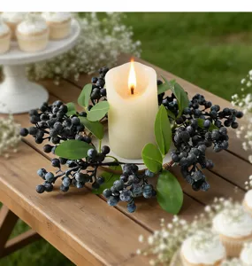 Detail of artificial blueberry candle ring with green leaves on a wooden table