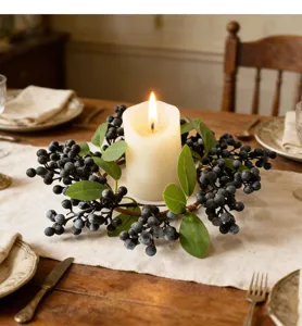 Close-up of artificial blueberry wreath surrounding a lit candle on a rustic dining table