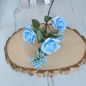 Primer plano de rosas artificiales azul claro y bayas de milán sobre rodaja de madera