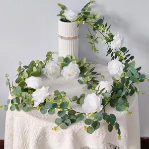 Vista detallada de guirnalda de rosas blancas artificiales y eucalipto para decoración.