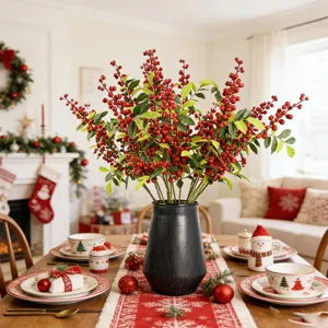 Bacche rosse artificiali festive con foglie verdi in vaso nero per decorazione domestica.