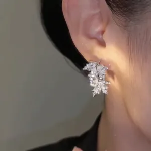 Primo piano di eleganti orecchini a lobo a foglia d'acero con zirconi brillanti.