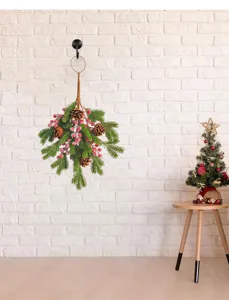 Traditional Christmas pinecone and red berry teardrop swag on a rustic white wall