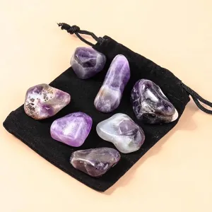 Polished purple amethyst tumbled stones on a black velvet drawstring pouch for healing