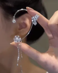 Primer plano de un ear cuff plateado con detalles de flor y mariposa giratorias