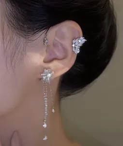Primer plano de ear cuff giratorio de flor y mariposa con borlas de cristal.