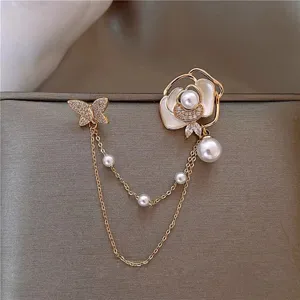 Detailed view of a gold shell butterfly and pearl flower brooch with double chains.