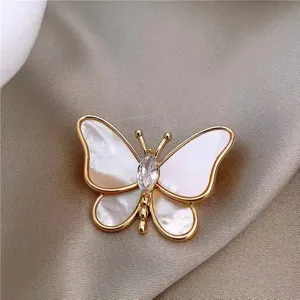 Detailed view of an elegant butterfly brooch with white shell wings and a central crystal.