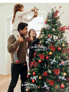 Happy family decorating a lush Christmas tree with glittery red and silver berry picks stems