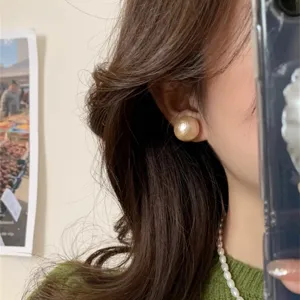 Close-up of a large vintage-style gold pearl earring worn on the ear
