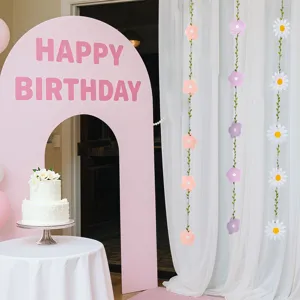 Close-up of decorative daisy and floral paper garlands in a pink birthday party scene