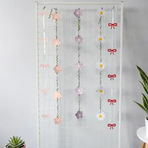 Variety of decorative paper flower and bow banners hanging on a white grid wall.