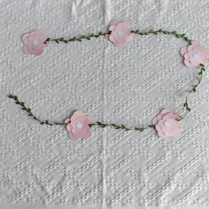 Pink paper flower garland with green leaf vine on white textured backdrop decoration