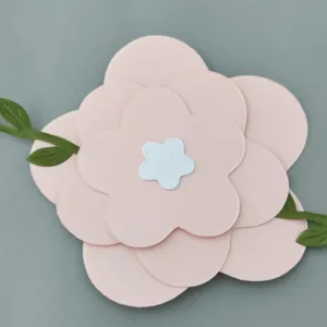 Detail view of a multi-layered pink paper flower with green leaves for party backdrops
