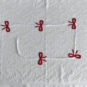 Detailed view of a festive red bow garland banner on textured white fabric background