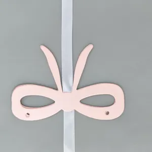 Detailed close-up of a pink paper bow decoration threaded with white ribbon for party banners