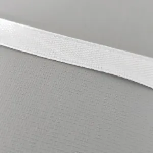 Macro detail showing the woven texture of a white ribbon for birthday party decorations.