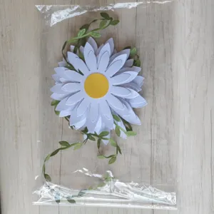 Handmade large white daisy paper flower decoration with green leaves in clear plastic bag