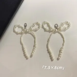 Detailed view of two elegant pearl bow-knot charms with lobster clasps, size 7.5x8cm