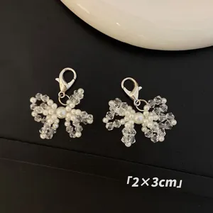 Close-up detailed view of handmade pearl and crystal bow charms with lobster clasp