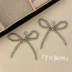 Detailed macro view of silver beaded bow charms measuring 7x8cm with lobster clasps.