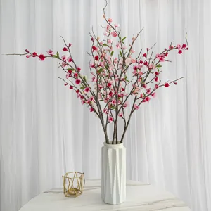 Élégantes fleurs de pêcher artificielles dans un vase en céramique blanc sur table marbre