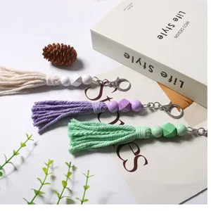 Primo piano di nappe di perline di legno boho in bianco, viola e verde per portachiavi fai-da-te.