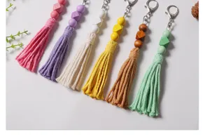 Primo piano di 6 portachiavi colorati con nappe e perline in legno su sfondo chiaro