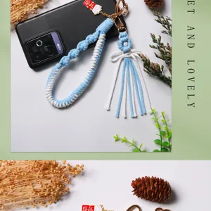 Close-up of handmade braided cotton rope keychain with flower knot and lucky cat charm