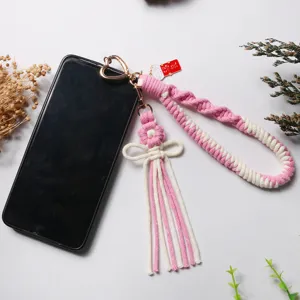 Unique handmade pink and white braided phone strap featuring a woven flower and tassel