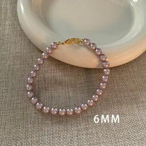 Detailansicht eines 6mm lila-rosa Perlenarmbands mit goldenem Verschluss auf Teller.