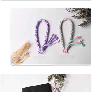 Detail view of two hand-woven braided phone lanyards in purple and pink-green