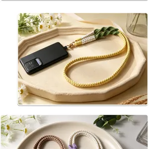 Detail view of hand-woven phone wrist strap with sturdy metal clasp in a cream tray.