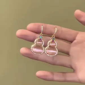 Detail view of pink cat's eye stone earrings in gourd shape with elegant gold finish