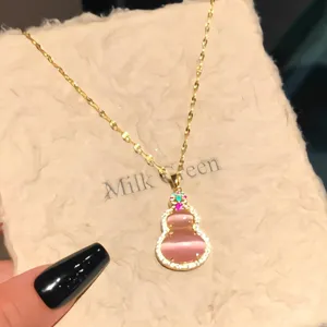 Detailed macro view of a pink cat's eye gourd pendant necklace with gold chain