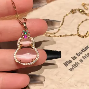 Close-up detail of a pink cat's eye stone gourd pendant necklace with a gold chain