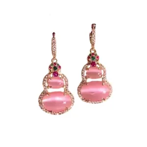 Detailed macro view of pink cat-eye stone gourd earrings with gold-plated setting and crystals