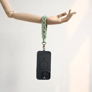 Elegant sage green handmade macrame phone wrist strap displayed on a wooden mannequin arm