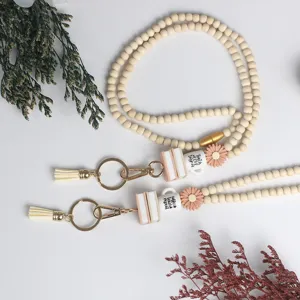 Wooden bead teacher lanyard detail, showing cute coffee mug and book charms with tassels.