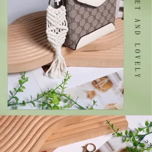 Close-up of white handmade macrame keychain on a stylish bag with wooden background