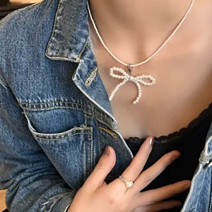 Elegant white pearl bow necklace shown in a detailed close-up shot with denim jacket