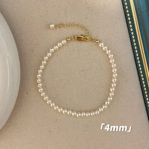 Nahaufnahme eines minimalistischen 4mm weißen Perlenarmbands mit goldenem Verschluss