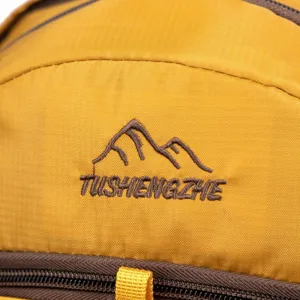 Detailed view of TUSHENGZHE embroidered mountain logo on durable yellow hiking backpack