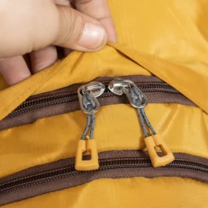 Close-up view of double zipper detail on yellow outdoor travel backpack with flap.