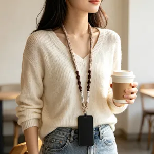 Minimalist woven phone lanyard with earth-tone colors worn by woman in cafe.