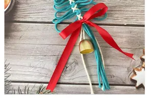 Détail d'une décoration de Noël tissée à la main avec ruban rouge et clochette dorée